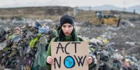 Woman activist holding placard poster on landfill, environmental pollution concept.