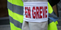 Closeup of man protesting in the street with cut and text in french : en greve, traduction in english : striking